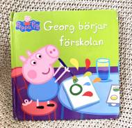 Boken Georg börjar förskolan baserat på barnprogrammet Greta Gris. På framsidan målar Georg och har penseln i högsta hugg.
