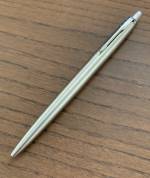 En Parker Jotter-penna i stål som ligger på ett brunt träbord.