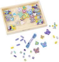 En omålad trälåda full med pärlor som liknar fjärilar och vanliga pärlor i ljusa färger.